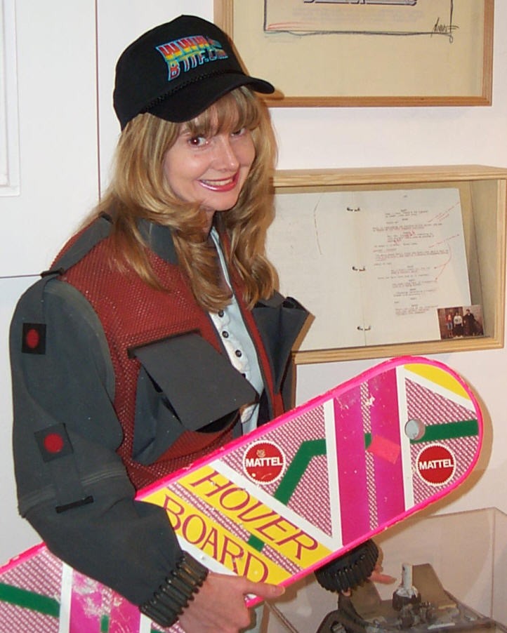 Tammy Castillo holding a Back to the Future hoverboard in front of framed Back to the Future memorabilia